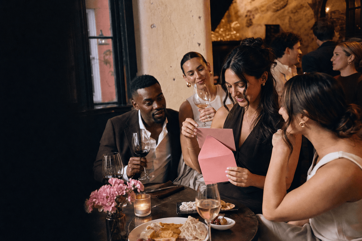 Friends opening a P.S. card at an intimate wine bar