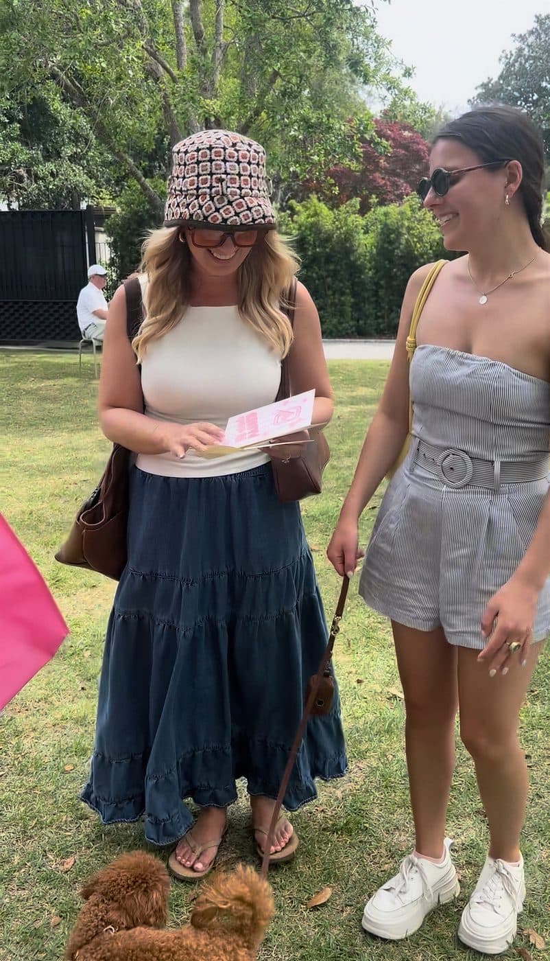 Two women reading a card with their poodles nearby